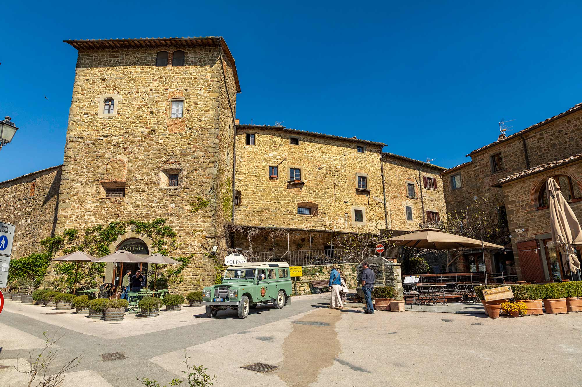 Land Rover parcheggiata nella piazza medievale di Volpaia con l'antica torre in pietra