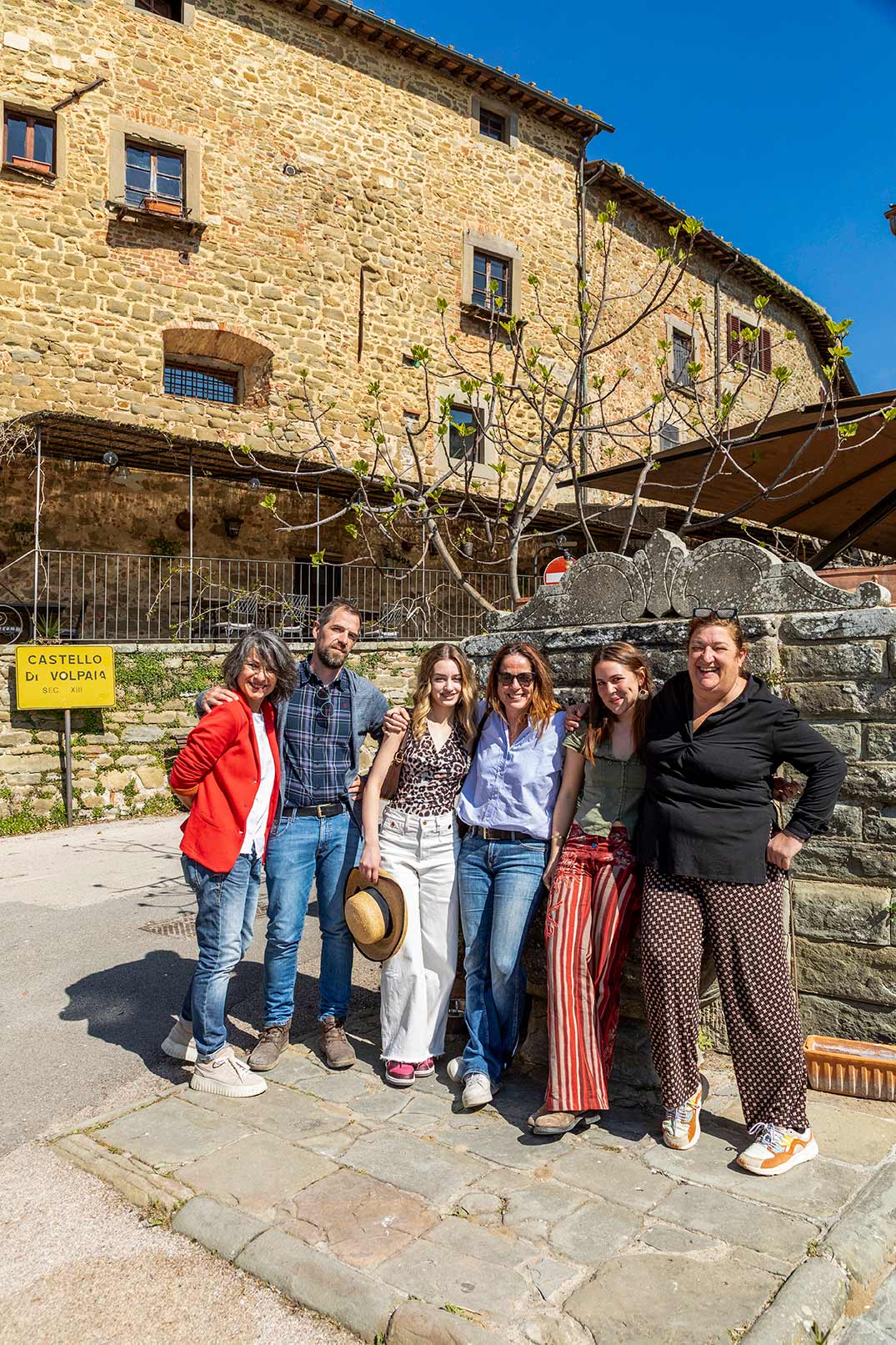 Sei ospiti in posa all'ingresso del Castello di Volpaia sotto un cielo blu brillante